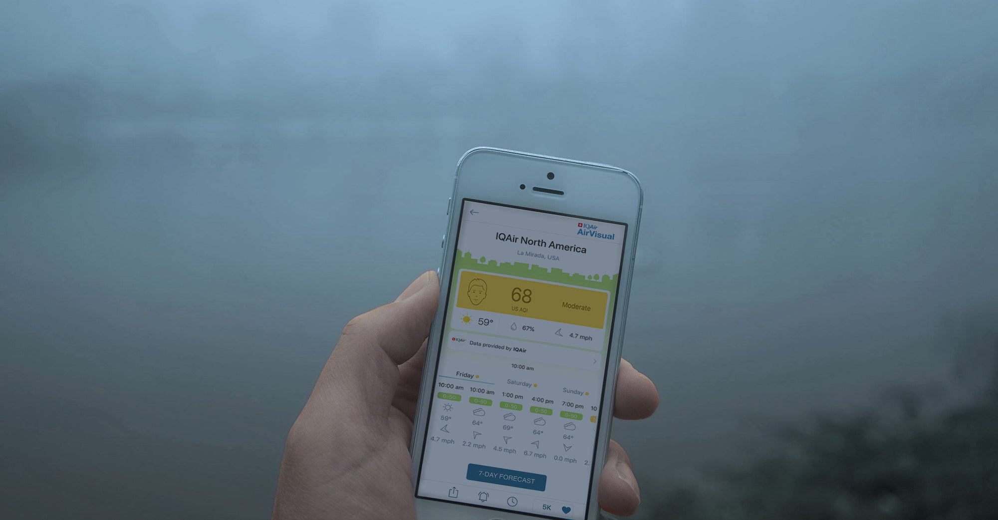 person using AirVisual App with air pollution in background